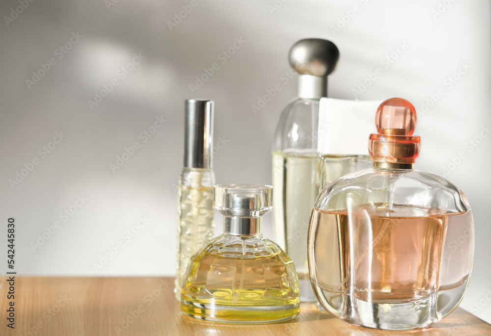 Various woman perfumes set on light background with shadows. Selective focus on front bottle Various woman perfumes set on light background with shadows. Selective focus on front bottle