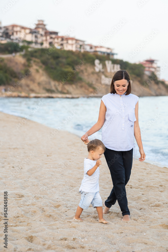 Happy family on beach vacation. Mother and little son walking and Happy mother and son walking, playing, laughing on the beach. Mother hugging child. Enjoying life. on thel beach at summer sunset. Happy family on beach vacation. Mother and little son walking and Happy mother and son walking, playing, laughing on the beach. Mother hugging child. Enjoying life. on thel beach at summer sunset.