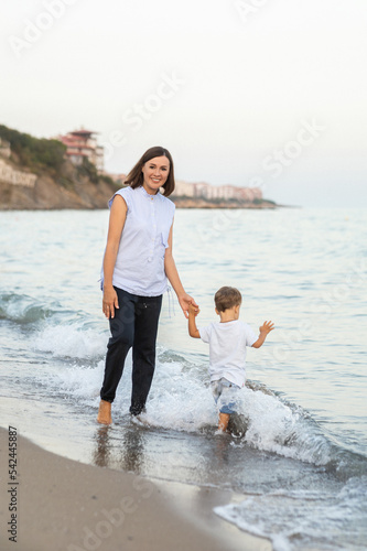 Happy  family on beach vacation. Mother and little son walking and Happy mother and son walking, playing, laughing on the beach. Mother hugging child. Enjoying life. on thel beach at summer sunset. photo