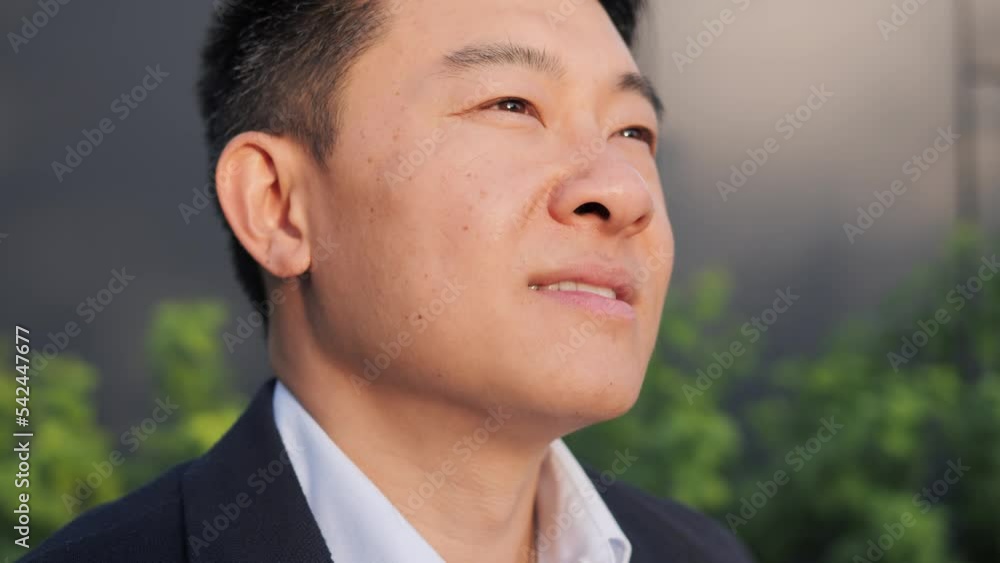 Portrait of a smiling handsome middle aged asian man looking ahead raising head. Enjoys Nature Fresh air and Dreaming. Concept of achievement, distant worker. Successful businessman. Motivation. Portrait of a smiling handsome middle aged asian man looking ahead raising head. Enjoys Nature Fresh air and Dreaming. Concept of achievement, distant worker. Successful businessman. Motivation.