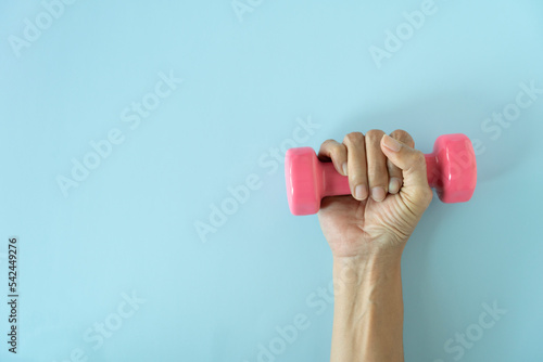woman hand holding pink dumbbell on blue table background, sport concept