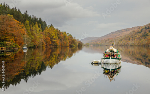 Peaceful scene of boat and reflection in Loch Oich with autumn vegetation photo