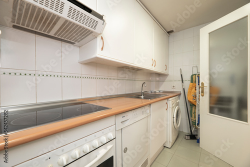 Fotobehang elongated kitchen room with white cabinets with matching appliances, dryer, wash