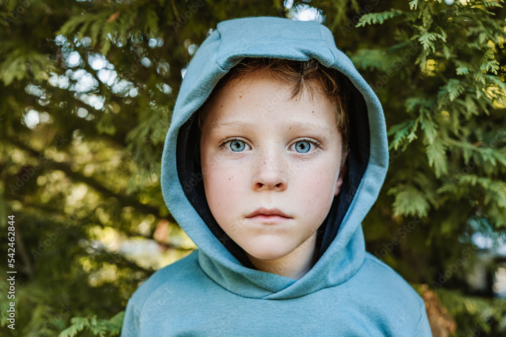 Unemotional child in hoodie in forest Unemotional child in hoodie in forest