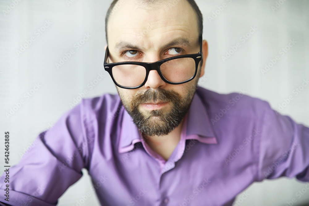 A cross-eyed bearded man is looking into the frame. Eye disease. The concept of an inexperienced specialist. Spy neighbor. A cross-eyed bearded man is looking into the frame. Eye disease. The concept of an inexperienced specialist. Spy neighbor.