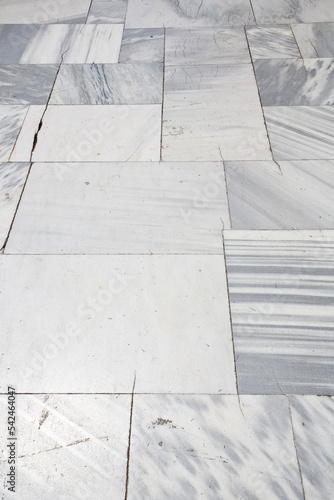 Old and cracked paving made with white marble stone blocks