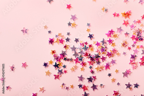 Multicolor holographic Stars Glitter Confetti on pink background. Festive backdrop  selective focus