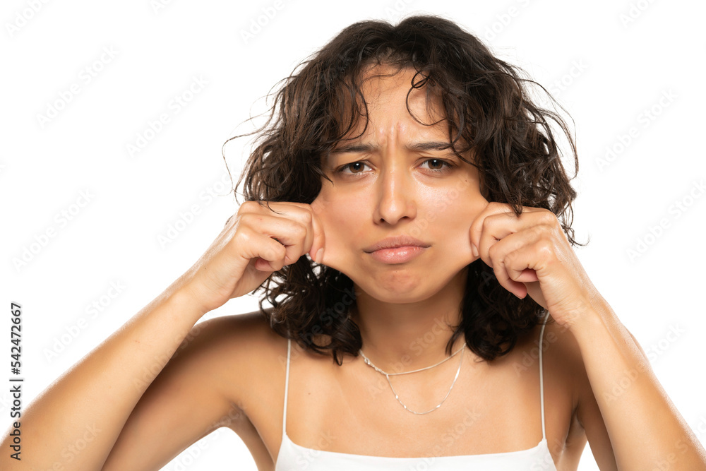 Portrait of young etnic woman, pulling her cheek skin on white background Portrait of young etnic woman, pulling her cheek skin on white background