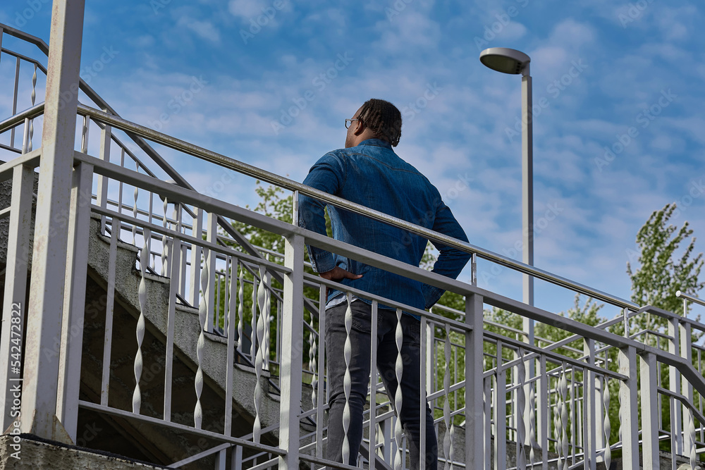 Dark-skinned man tunes in to climb a high staircase, overcoming the fear of heights. Overcoming his fears, a man comes out victorious. African Guy Stands Before Climbing Up Dark-skinned man tunes in to climb a high staircase, overcoming the fear of heights. Overcoming his fears, a man comes out victorious. African Guy Stands Before Climbing Up