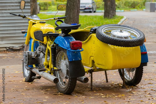 Yellow Soviet police motorcycle Ural with sidecar in urban park. Back view photo