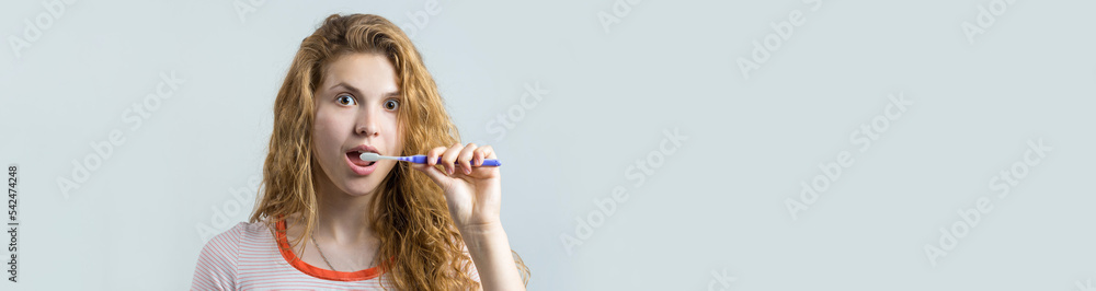 Portrait of a smiling cute woman with red curly hair holding toothbrush isolated on a white background Portrait of a smiling cute woman with red curly hair holding toothbrush isolated on a white background