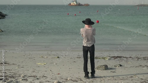 Albino man walking on the beach holding a vintage video camcoder photo
