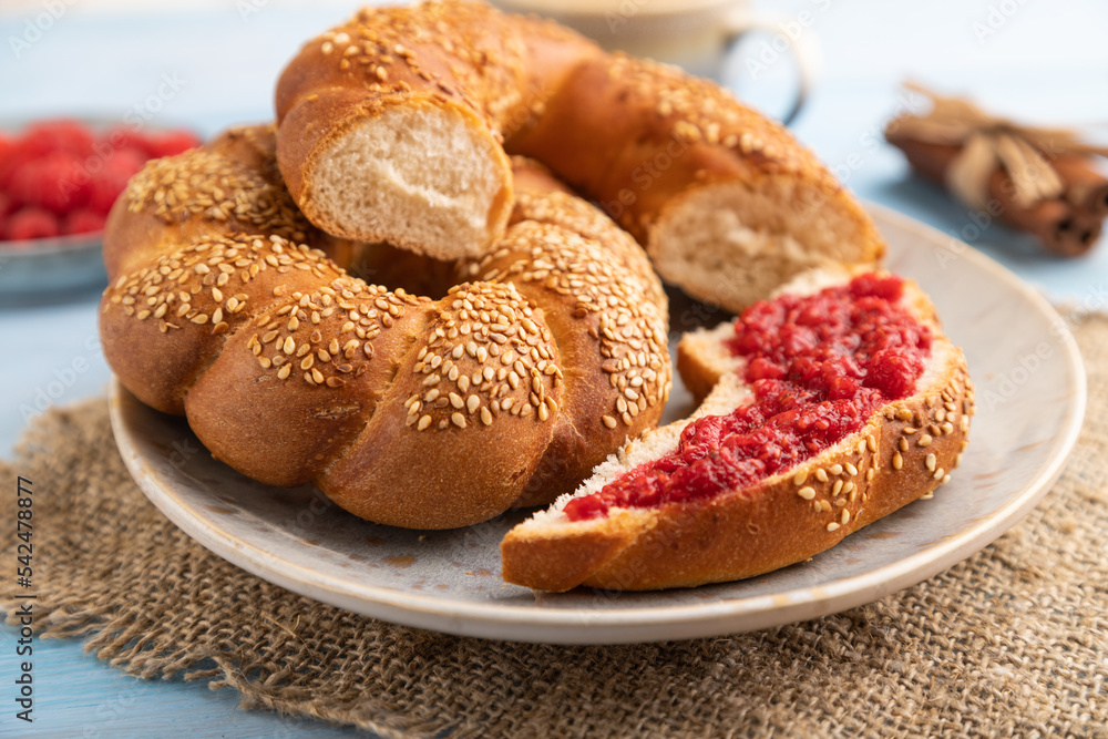 Homemade sweet bun with raspberry jam and cup of coffee on a blue wooden. side view, selective focus. Homemade sweet bun with raspberry jam and cup of coffee on a blue wooden. side view, selective focus.