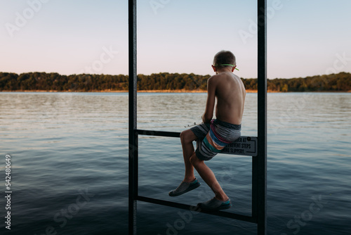 Young boy fishing in lake off dock at sunset photo