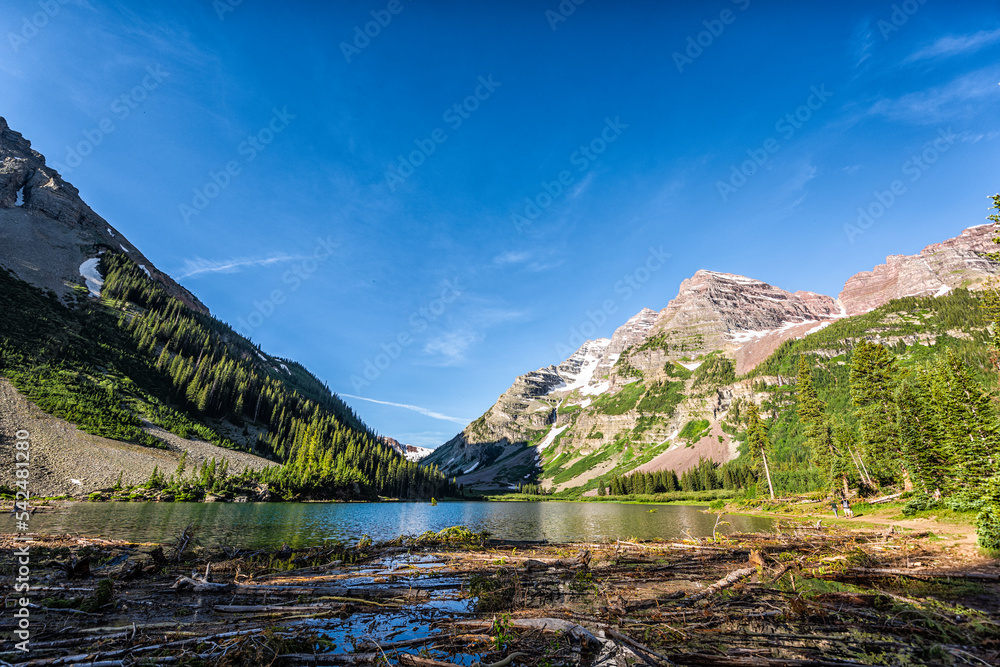 Aspen, Colorado Maroon Bells area with landscape view of Crater lake and rocky mountain peak in summer on trail wide angle view with avalanche debris logs on water