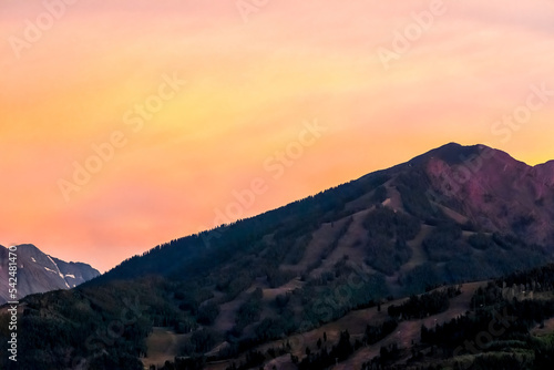 Pastel orange sunset in Aspen, Colorado with rocky mountains peak in autumn and vibrant yellow color at twilight over buttermilk ski resort