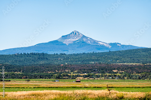 Rocky Mountains view of Wilson peak from highway 145 in San Juan region of Colorado near Telluride with agriculture field on summer sunny day with blue sky