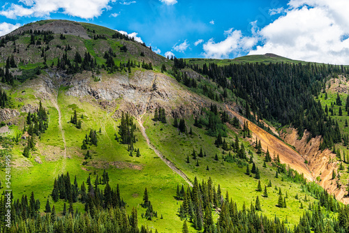 Lush green mountain alpine meadow hill and blue sky clouds near Ouray, Colorado with San Juan rocky mountains in summer from Million Dollar Highway photo