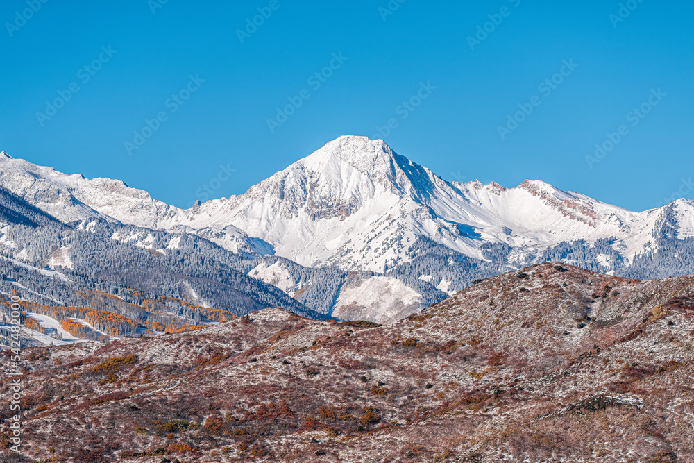 Aspen, Colorado with blue clear sky by Capitol Mt Daly Snowmass mountain peak ridge closeup in autumn fall season covered in winter snow