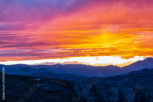 Aspen, Colorado rocky mountains range silhouette at vibrant colorful sunset of orange purple pink sky light with clouds in cloudy sky