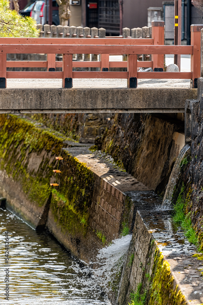 Small red vermilion bridge over Enako river in Takayama, Japan of Gifu prefecture with water flowing in early spring in traditional village Small red vermilion bridge over Enako river in Takayama, Japan of Gifu prefecture with water flowing in early spring in traditional village