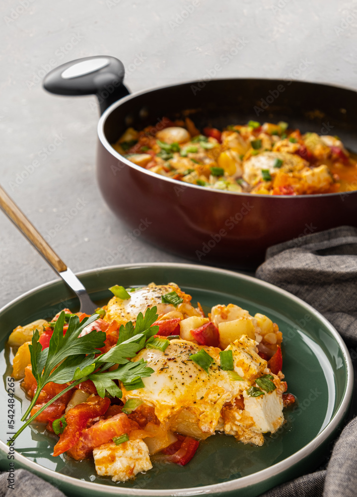 Shakshuka in a frying pan with tomatoes in vegetable sauce with cheese. A dish of fried eggs in a sauce of tomatoes, pepper, onion, garlic and seasonings. Vertical orientation, copy space, close-up Shakshuka in a frying pan with tomatoes in vegetable sauce with cheese. A dish of fried eggs in a sauce of tomatoes, pepper, onion, garlic and seasonings. Vertical orientation, copy space, close-up