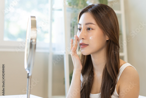 Fresh healthy skin, beautiful smile of asian young woman, girl looking at mirror, applying moisturizer on her face, putting cream treatment before make up cosmetic routine at home. Facial Beauty. Free Download Fresh healthy skin, beautiful smile of asian young woman, girl looking at mirror, applying moisturizer on her face, putting cream treatment before make up cosmetic routine at home. Facial Beauty. - GFXLoad