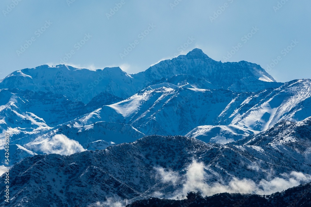 Landscape of range snowy mountains under cloudy blue sky