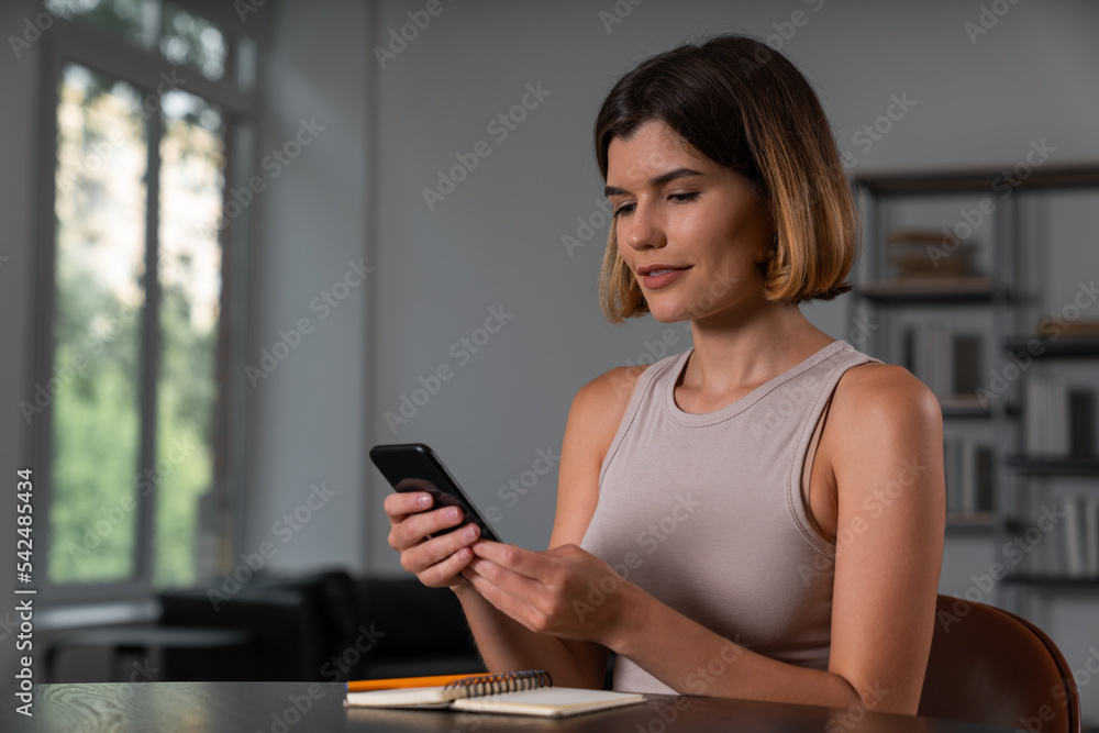 Thoughtful businesswoman in casual wear holding smartphone typing message