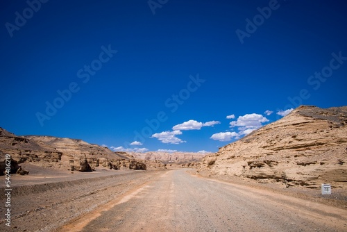 Beautiful view of a gravel road line by rocky cliffs