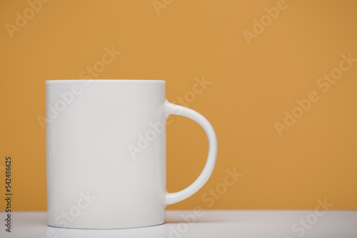 White mug mockup, close-up, yellow background.
