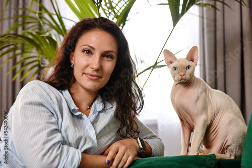 Tableau sur toile Portrait of young woman holding cute cat with blue eyes