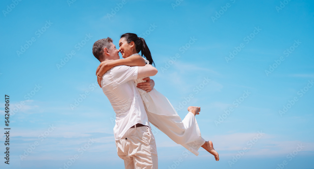 Young couple in love outdoor. Happy man Hugging and laughing to his woman romantic at tropical beach. Girlfriend with boyfriend resting travel at sunrise in summer.