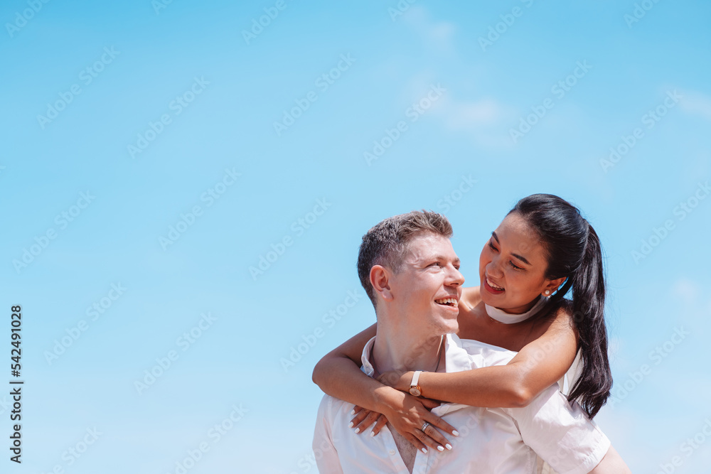 Young couple in love outdoor. Happy man giving piggyback ride to his woman and laughing at tropical beach. Girlfriend getting piggyback ride from boyfriend at sunrise in summer. Young couple in love outdoor. Happy man giving piggyback ride to his woman and laughing at tropical beach. Girlfriend getting piggyback ride from boyfriend at sunrise in summer.