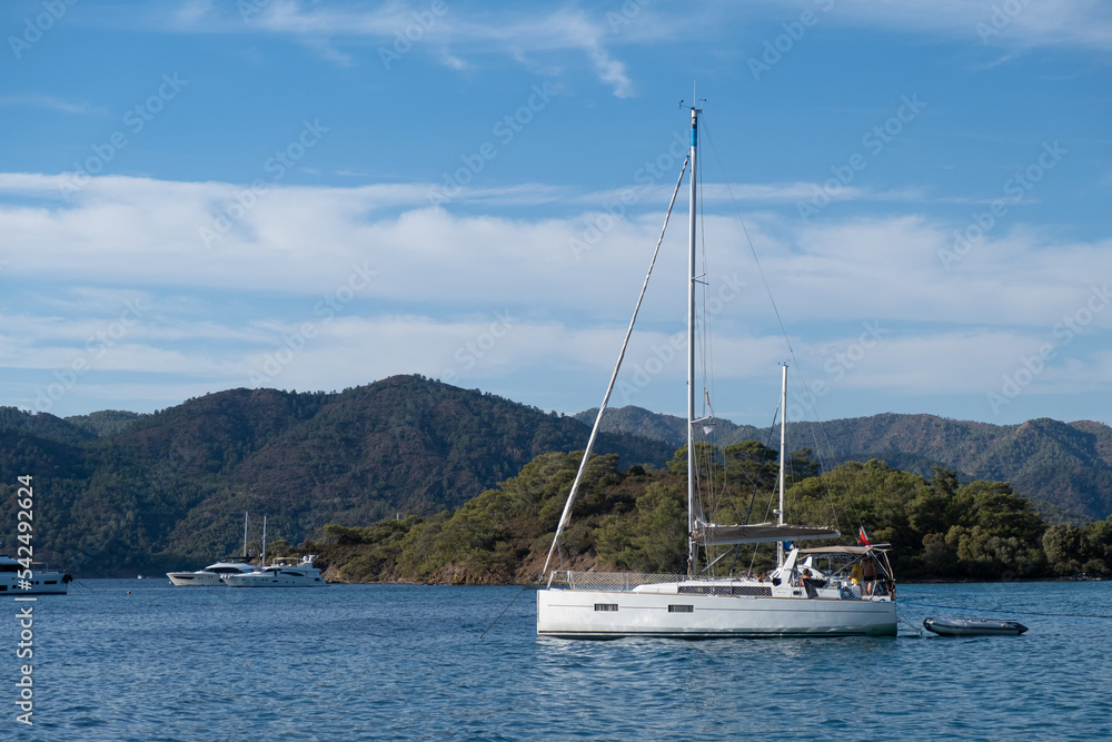 Beautiful bay with sailing boat, yacht in turquoise sea and mountains, luxury holidays or sailing regata sports.