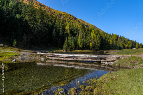 Serpentine river among the mountain peaks. Mountain lake reflects the autumn landscape of the forest with yellow leaves. Stones in a mountain river. 