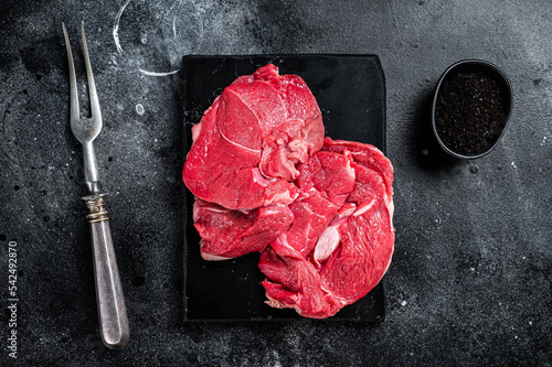 Raw Mutton fillet steaks from leg, uncooked lamb meat. Black background. Top view