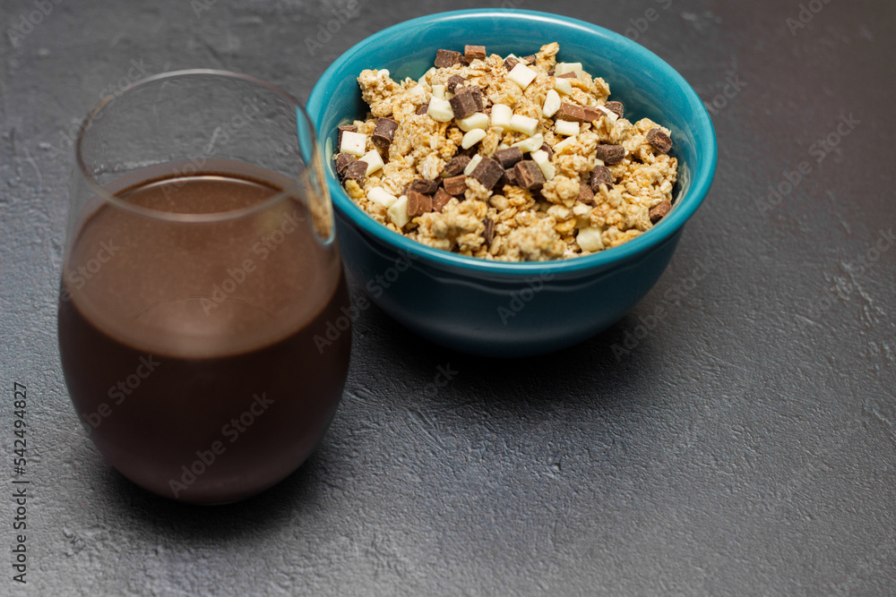 Sweet chocolate granola cereals and chocolate milk, in a blue bowl on a black background Sweet chocolate granola cereals and chocolate milk, in a blue bowl on a black background