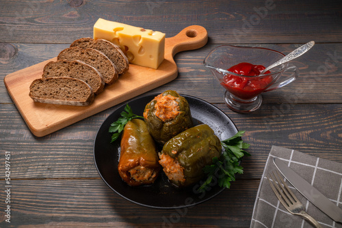 stuffed bell peppers with cheese and sliced bread on a wooden background
