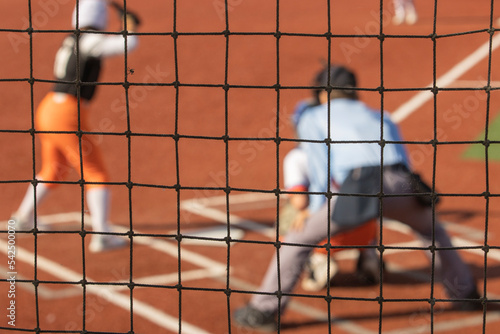 Fastpitch softball game on field focus on net.