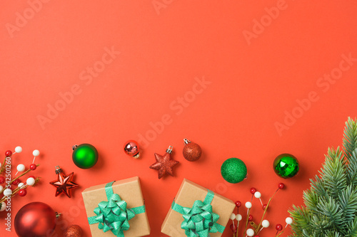 Christmas and New Year greeting card with gift box, ornaments and decorations on red background. Top view, flat lay