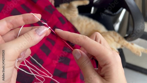 POV hands with tunisian hook for crochet craft making loops to start knitting. Winter hobbies at cozy home with yarn and checkered plaid. Film grain texture. Soft focus. Live camera. Blur. Candid photo