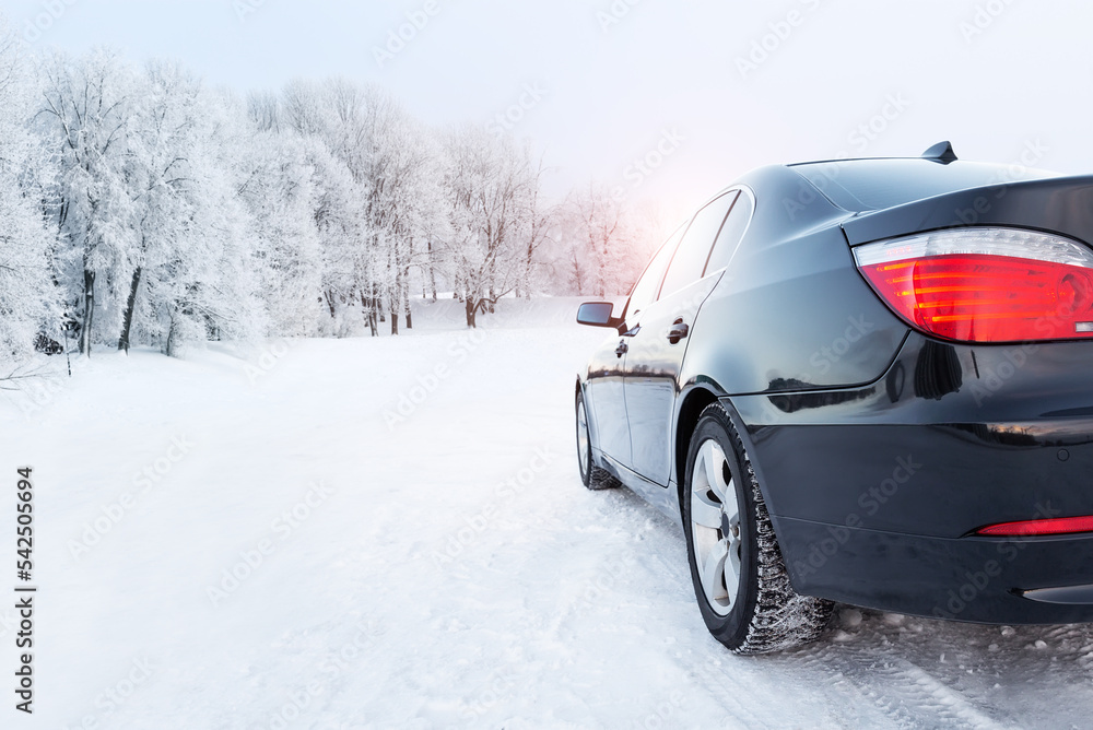 Black car on a winter road in a snowy forest, winter journey.