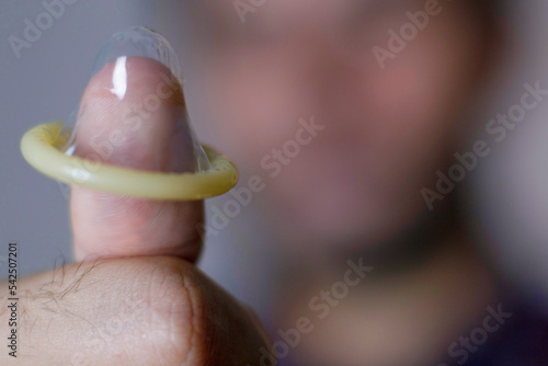 Holding condom with thumb  safe sex positive. Man holding condom. Macro photography.