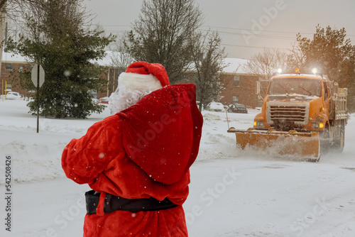 фотографія Santa Claus is walking on road with gifts near truck to clear road
