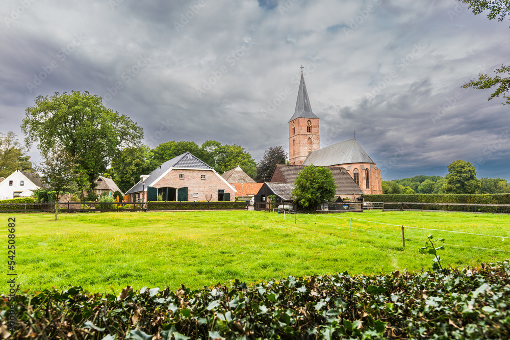 Summer cityscape Drents village Rolde with Jacobuskerk and farms seen from the Hunebedweg against a background of stormy wee with dark gray sky and rain clouds