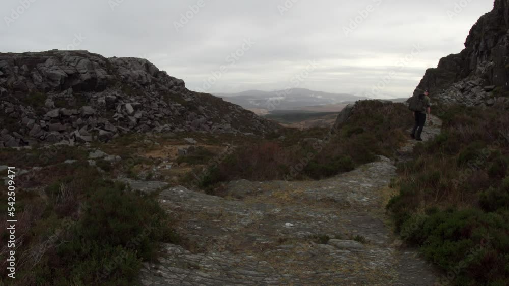 A man backpacking along an overcast mountain trail to a viewpoint A man backpacking along an overcast mountain trail to a viewpoint