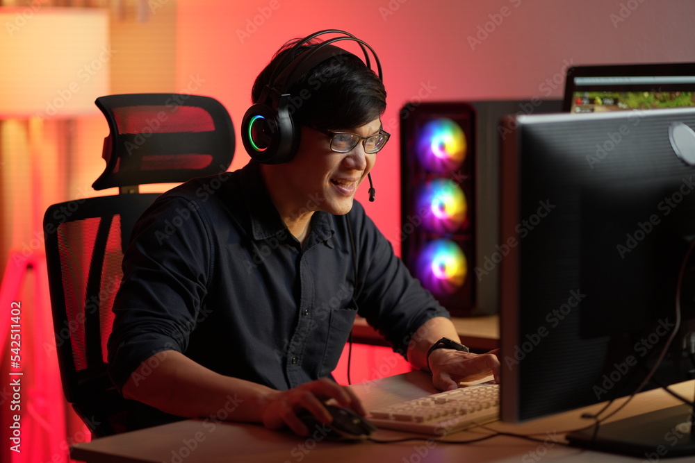 Professional Gamer Playing First-Person Shooter Online Video Game on His Powerful Personal Computer. Room and PC have Colorful Neon Led Lights. Young Man Cozy Evening at Home.