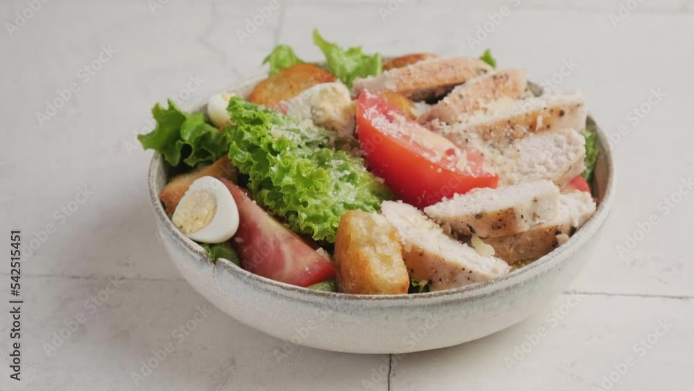 Sprinkle parmesan cheese in a plate with Caesar chicken salad. Healthy food. 4k video Sprinkle parmesan cheese in a plate with Caesar chicken salad. Healthy food. 4k video