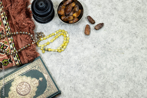 lantern and Holy Quran with Arabic calligraphy meaning of Al Quran and prayer mat , rosary muslim and dates fruits